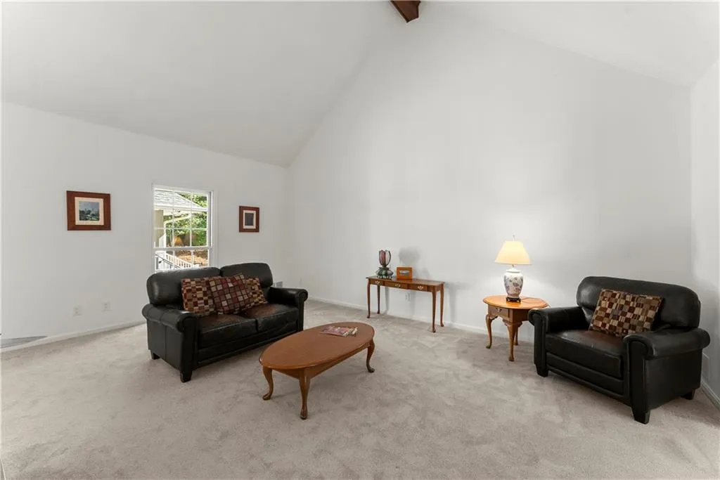 Living room featuring high vaulted ceiling, beamed ceiling, and light carpet