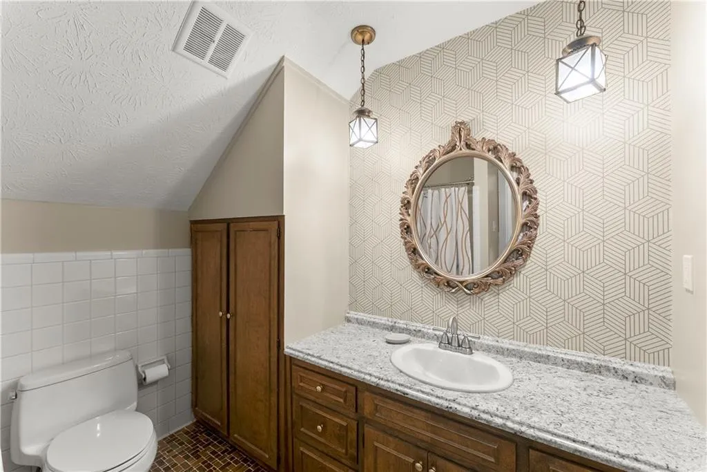 Full bathroom with vaulted ceiling, tile walls, vanity, a textured ceiling, and tile patterned flooring
