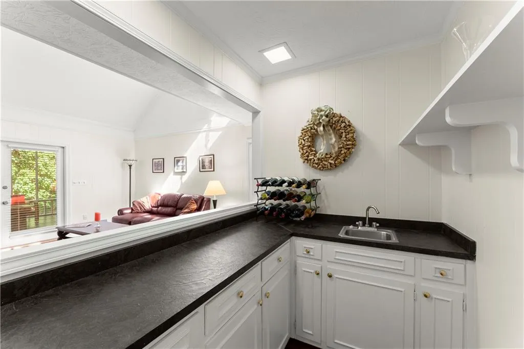 Indoor wet bar featuring ornamental molding and vaulted ceiling
