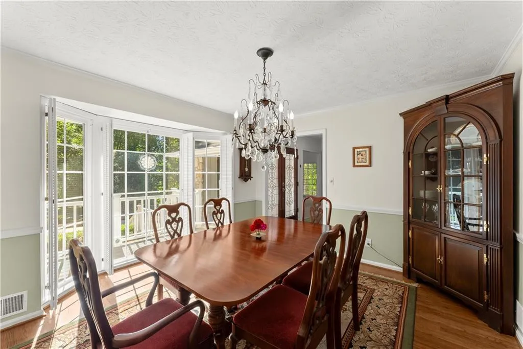 Dining room featuring a chandelier, a textured ceiling, wood finished floors, and ornamental molding