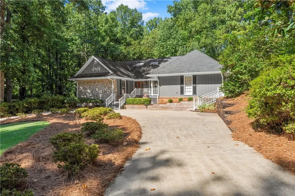 Single story home featuring a porch, concrete driveway, a shingled roof, and brick siding