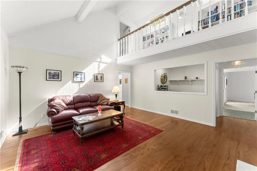 Living area with high vaulted ceiling, wood finished floors, beam ceiling, and wooden walls