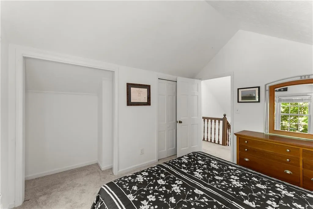 Bedroom with light colored carpet, vaulted ceiling, and a closet