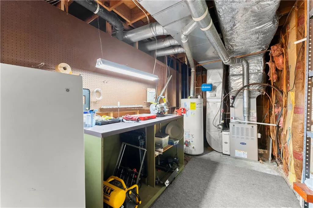 Basement featuring a workshop area, gas water heater, heating unit, and freestanding refrigerator