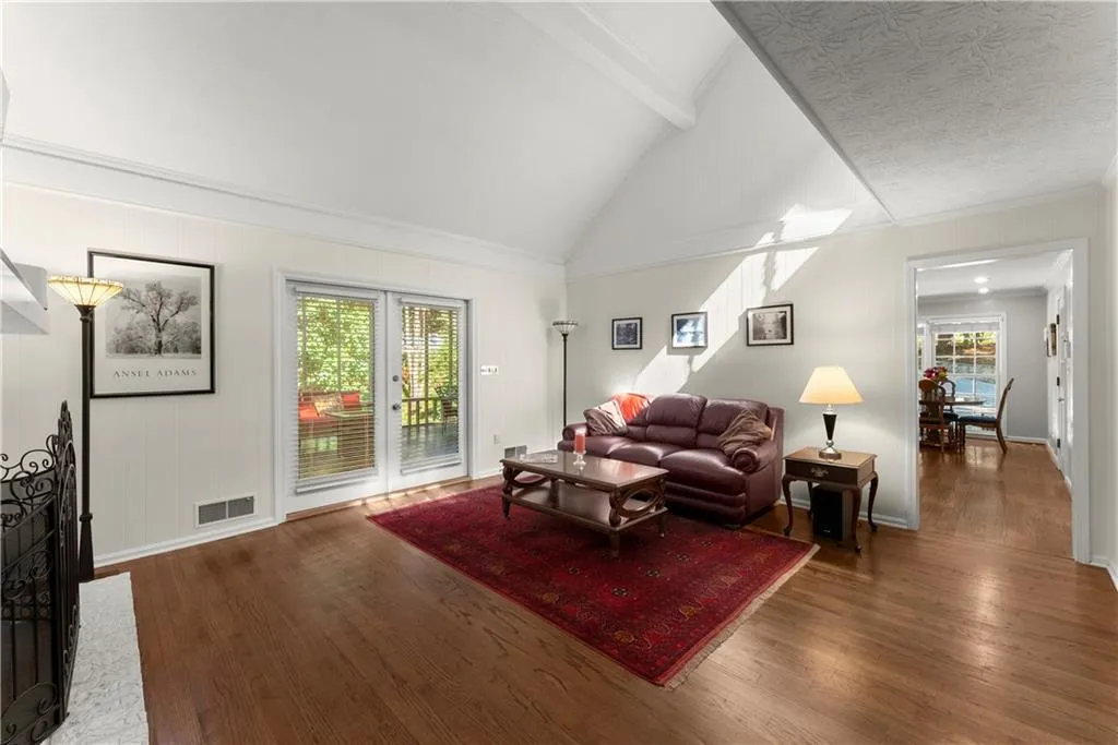 Living area featuring beam ceiling, wood finished floors, high vaulted ceiling, and ornamental molding