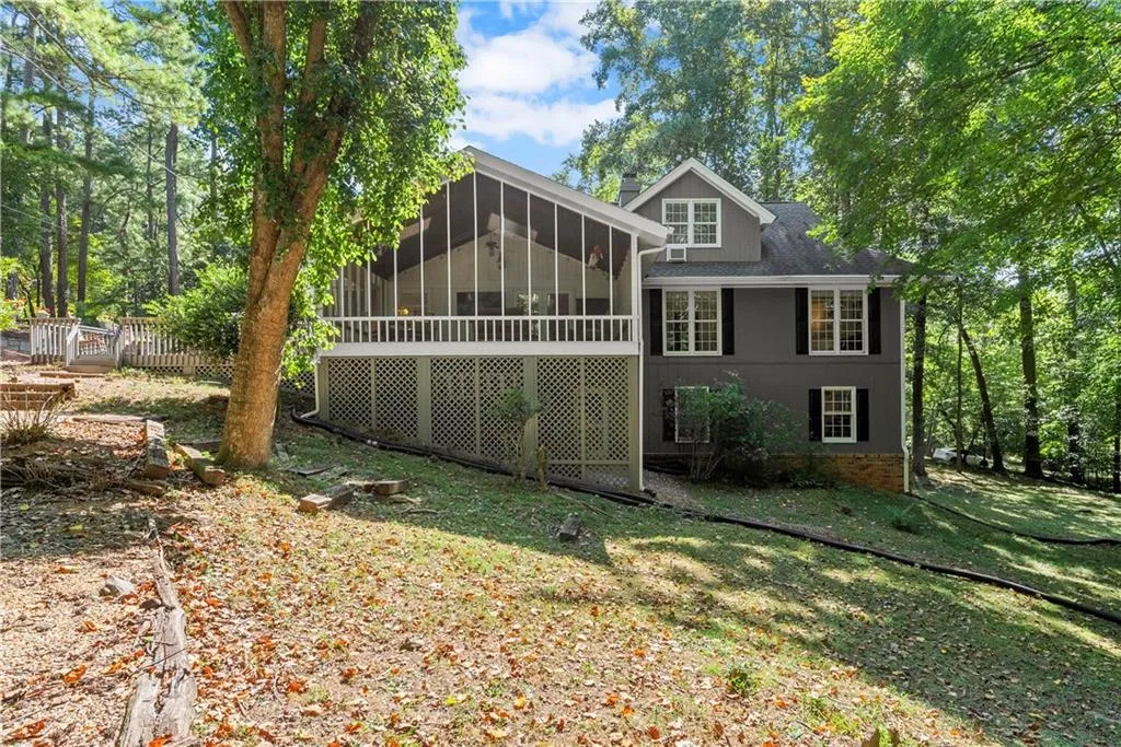 Rear view of property featuring a sunroom and roof with shingles