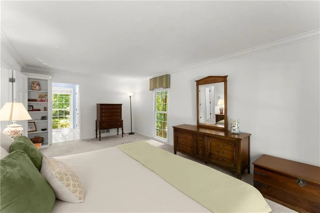Bedroom with ornamental molding, light colored carpet, and multiple windows