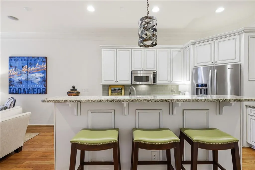 3.Kitchen with a kitchen bar, white cabinets, stainless steel appliances, light wood-style flooring, and tasteful backsplash