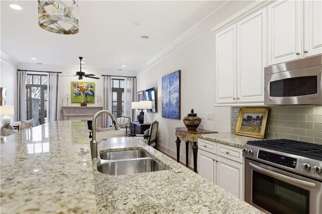 4.Kitchen with open floor plan, stainless steel appliances, white cabinets, light stone countertops, and backsplash