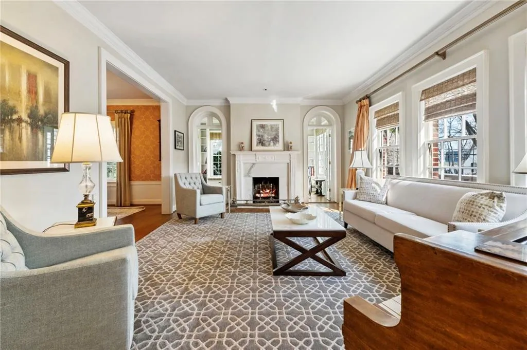 Living area featuring crown molding, a fireplace, wallpapered walls, and dark wood-style floors