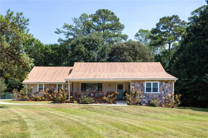 Split-level exterior featuring stone and siding finishes, a covered front porch, and a light brown shingled roof