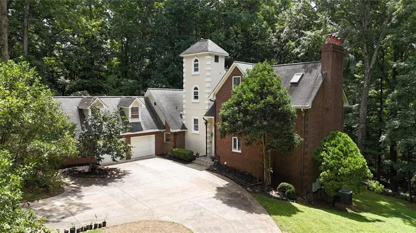 Stately brick and stucco residence featuring a prominent tower architectural element