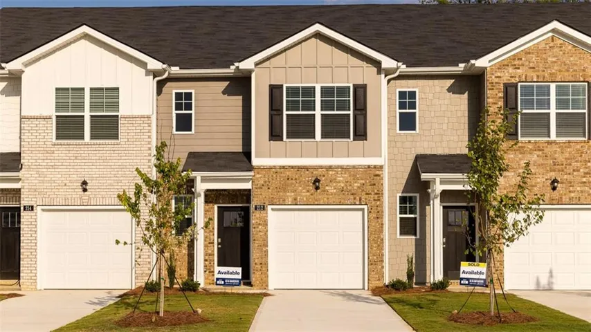 Contemporary townhomes featuring brick and siding exteriors, attached garages, paved driveways, and mature landscaping
