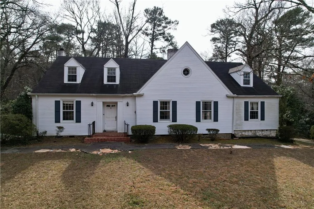 New england style home with a chimney and a front lawn
