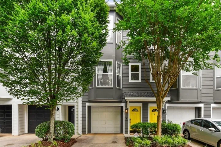 Contemporary townhouse exterior featuring gray siding, white trim, and a white garage door