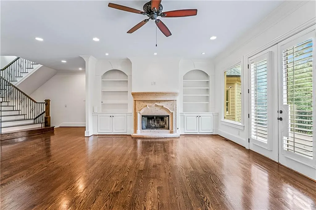 Unfurnished living room featuring dark wood-style floors, recessed lighting, ceiling fan, a fireplace with raised hearth, and stairway