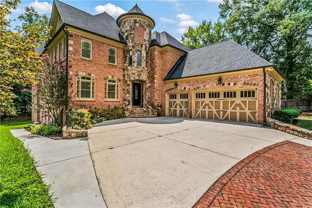 View of front of house with a garage, brick siding, driveway, and roof with shingles