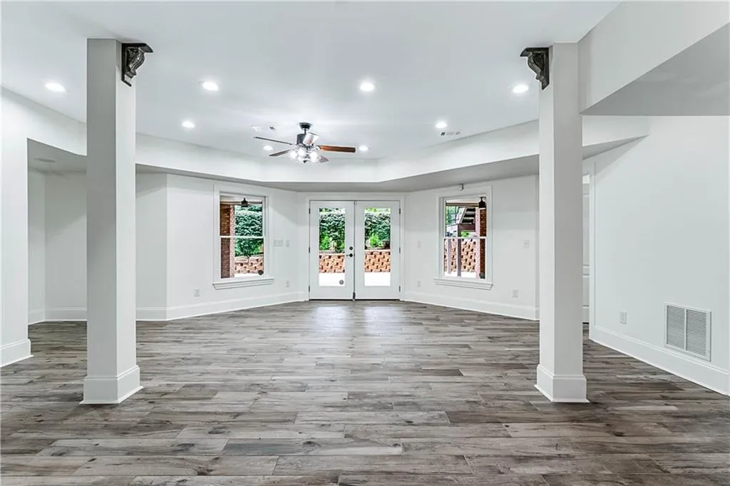 Unfurnished living room with plenty of natural light, recessed lighting, wood finished floors, and french doors
