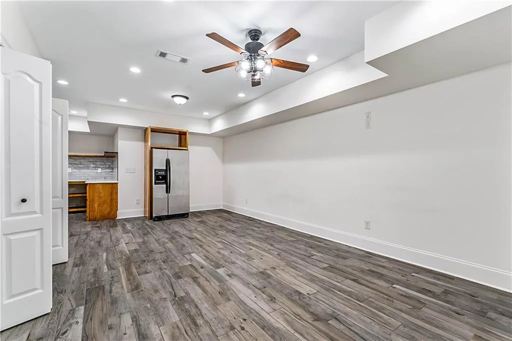 Basement living room featuring dark wood-style flooring, a ceiling fan, and recessed lighting