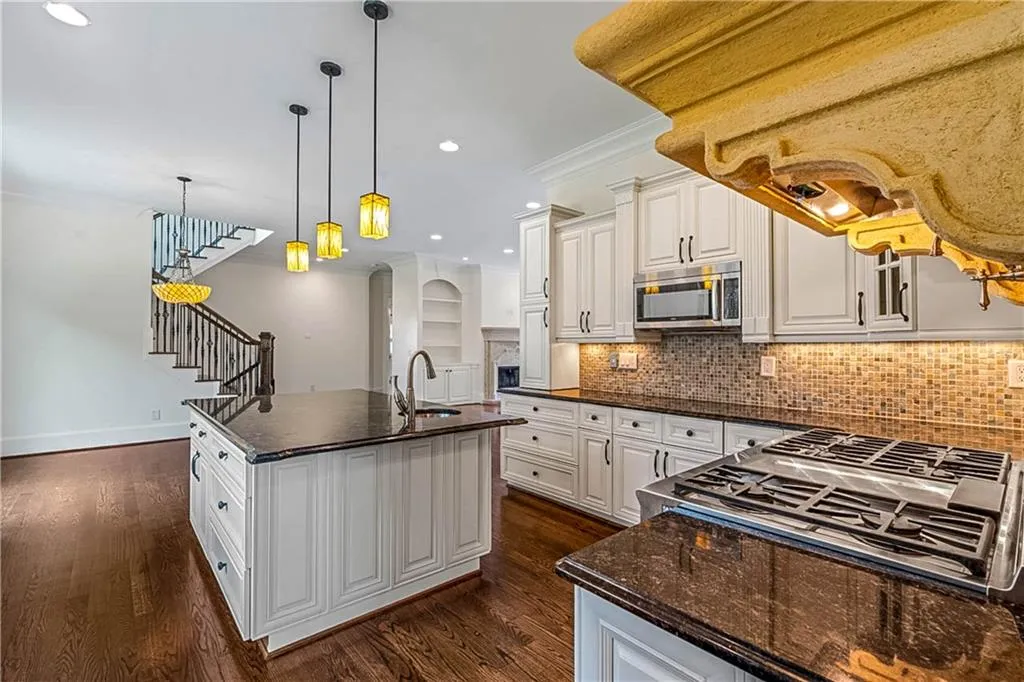 Kitchen featuring decorative light fixtures, crown molding, tasteful backsplash, a kitchen island with sink, and stainless steel appliances