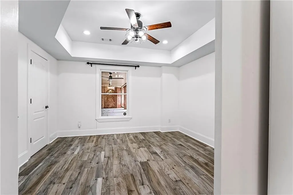 Empty room featuring wood finished floors, a tray ceiling, ceiling fan, and recessed lighting