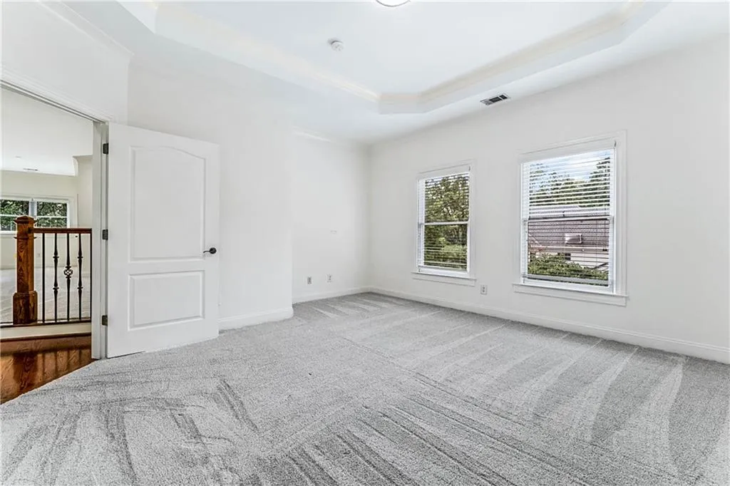 Carpeted spare room featuring a raised ceiling and ornamental molding