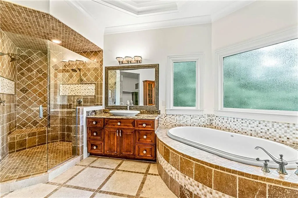 Bathroom featuring a bath, vanity, a shower stall, inlaid floor details, and crown molding