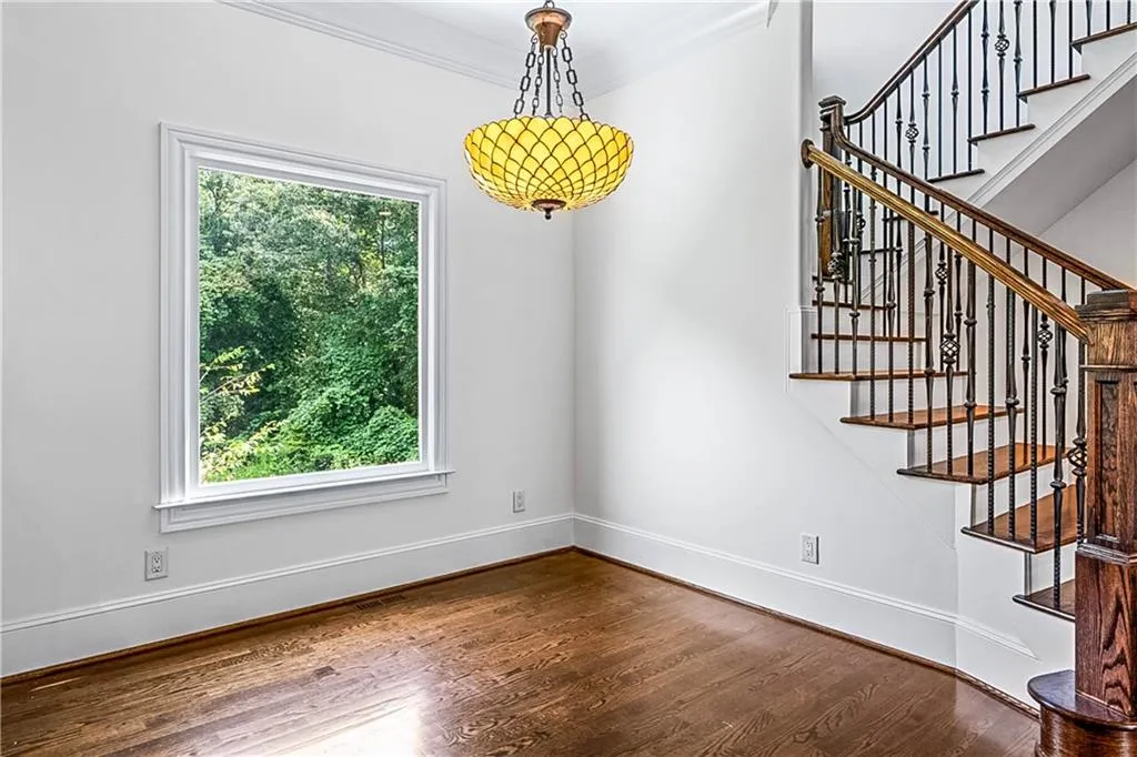 Unfurnished dining area with dark wood-style flooring, ornamental molding, and stairs