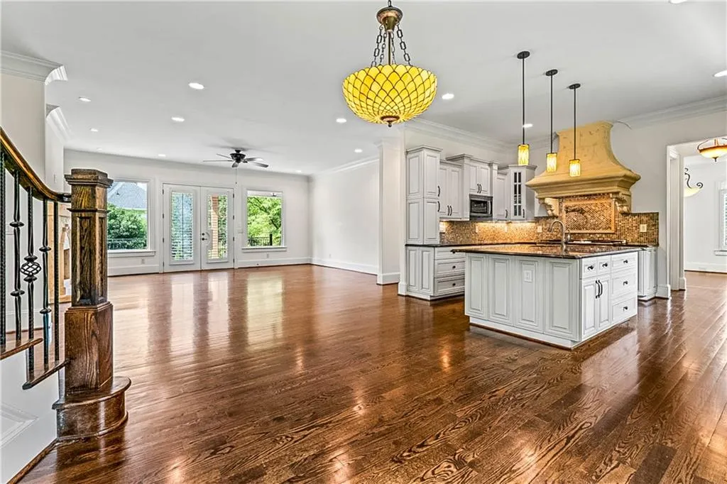 Kitchen with open floor plan, crown molding, pendant lighting, dark wood-style floors, and backsplash