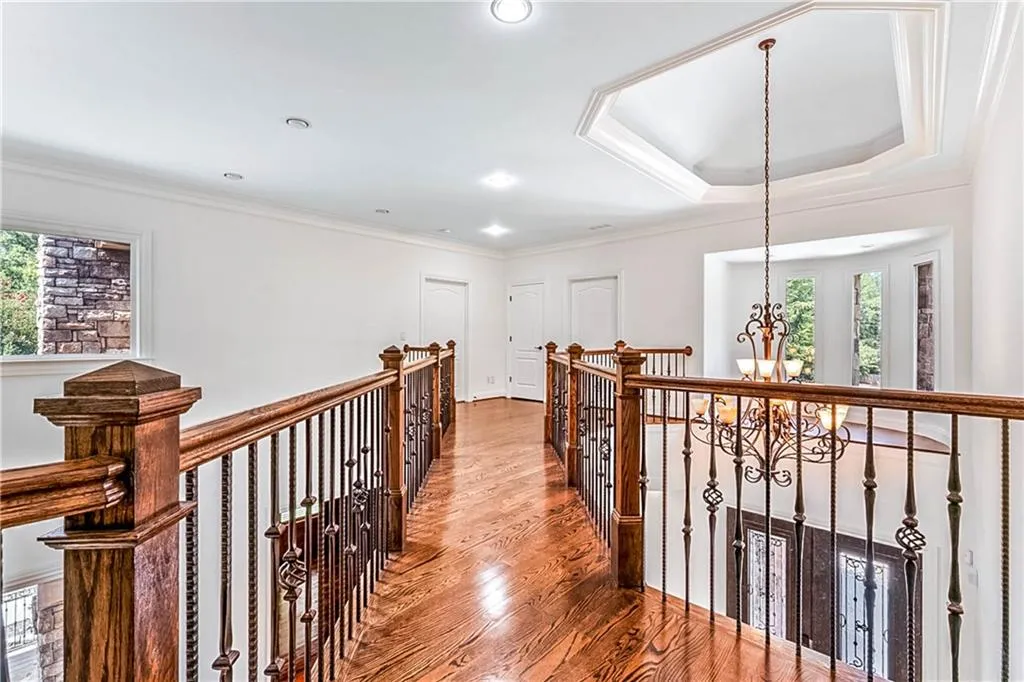 Hall featuring a chandelier, crown molding, wood finished floors, recessed lighting, and a raised ceiling