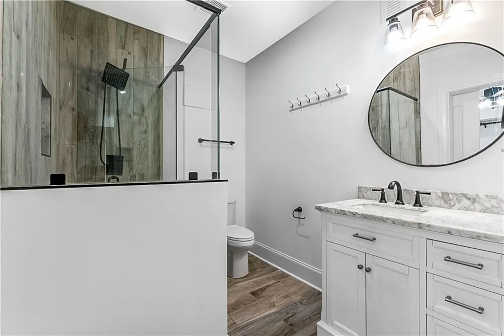Bathroom with a marble finish shower, vanity, and light wood-type flooring