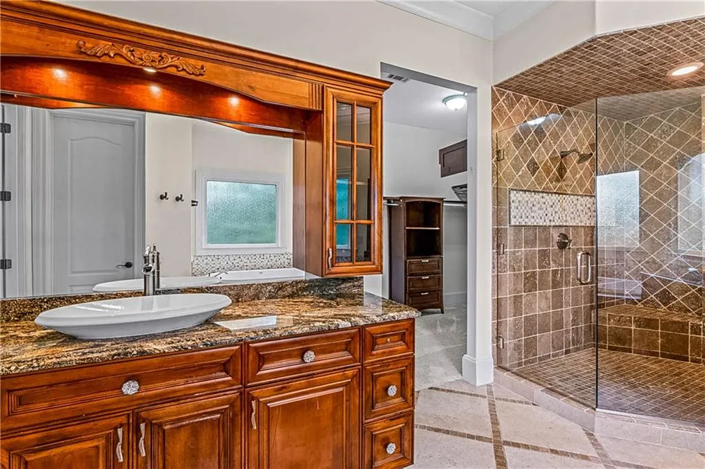 Full bath featuring a stall shower, vanity, and inlaid floor details