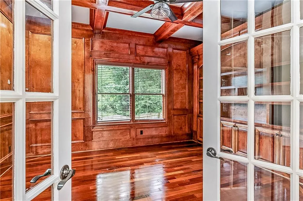 Elegant office featuring hardwood / wood-style flooring, coffered ceiling, wooden walls, beamed ceiling, and french doors