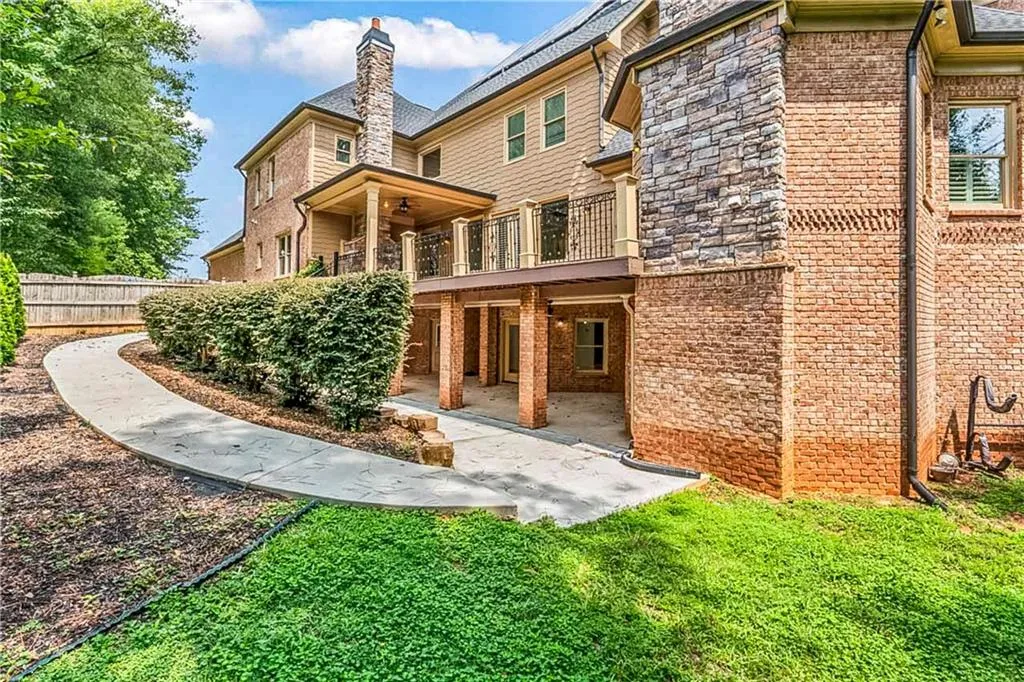 Back of property with a balcony, brick siding, and a patio area