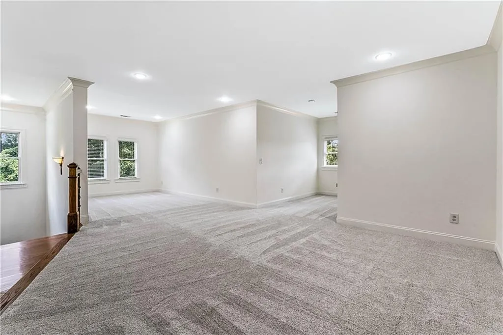 Unfurnished living room with crown molding, light colored carpet, and recessed lighting