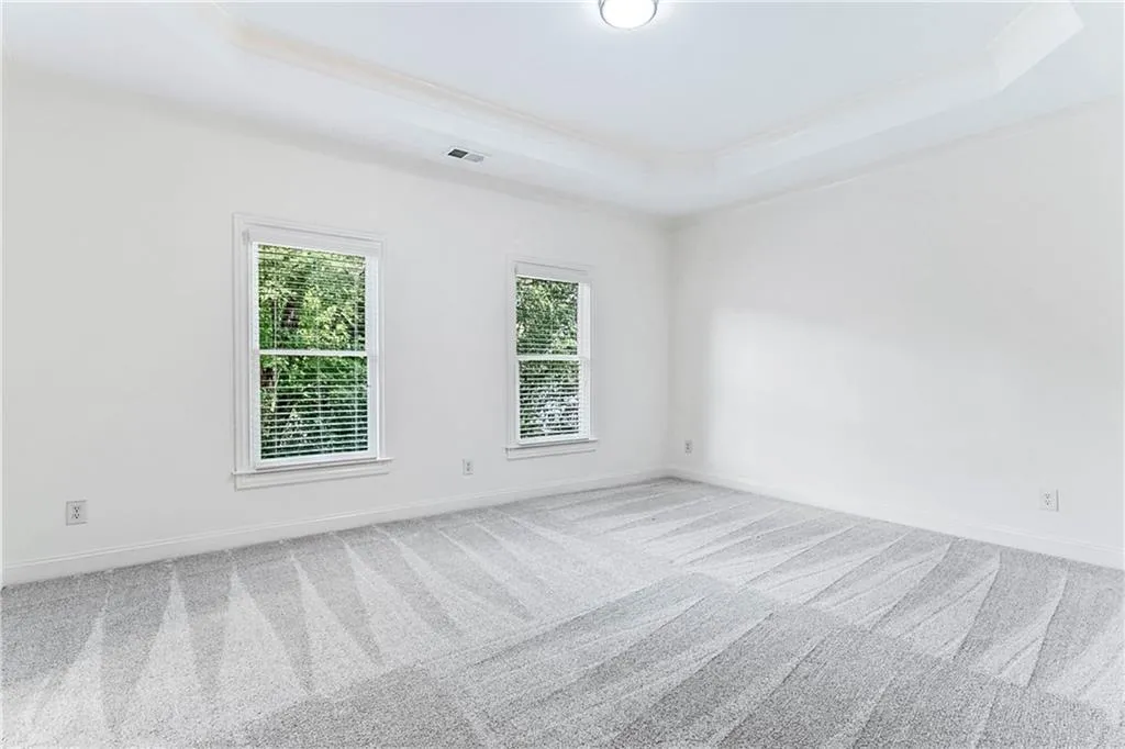 Spare room featuring a raised ceiling, carpet floors, and crown molding