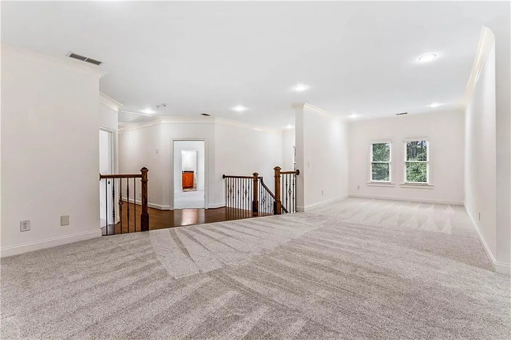 Large entertainment or play room featuring dark colored carpet, ornamental molding, and recessed lighting