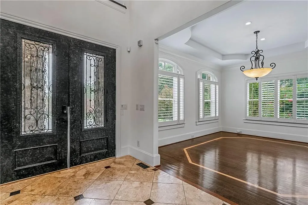 Tiled entrance foyer with a raised ceiling, healthy amount of natural light, and crown molding
