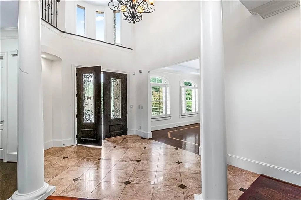 Foyer featuring ornate columns, plenty of natural light, a high ceiling, tile patterned flooring, and a chandelier