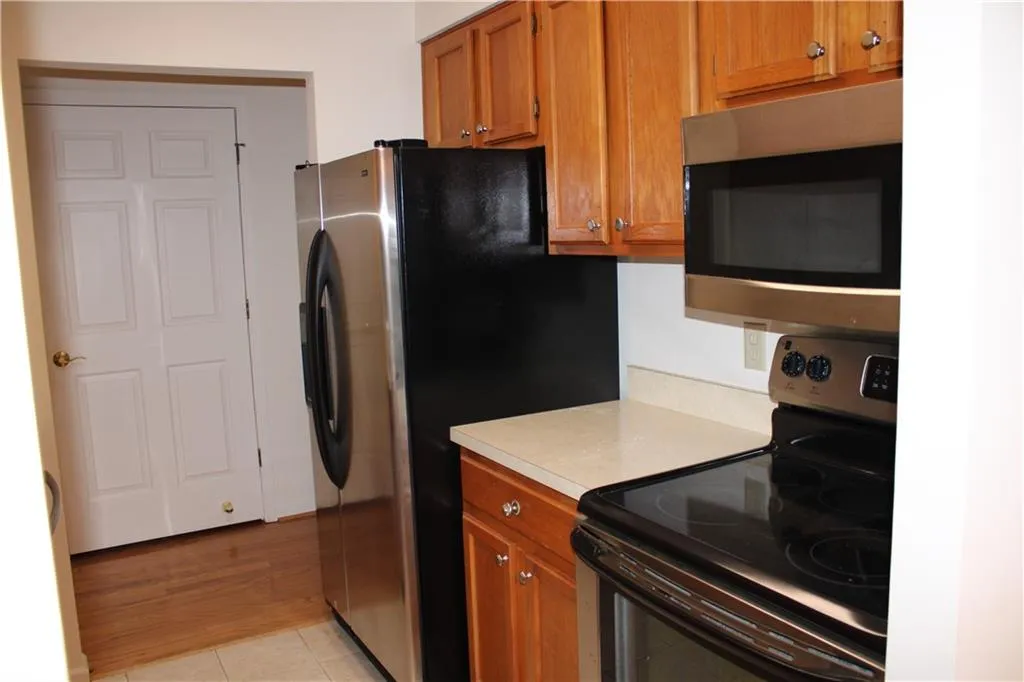 Kitchen with tile floors and appliances with stainless steel finishes.