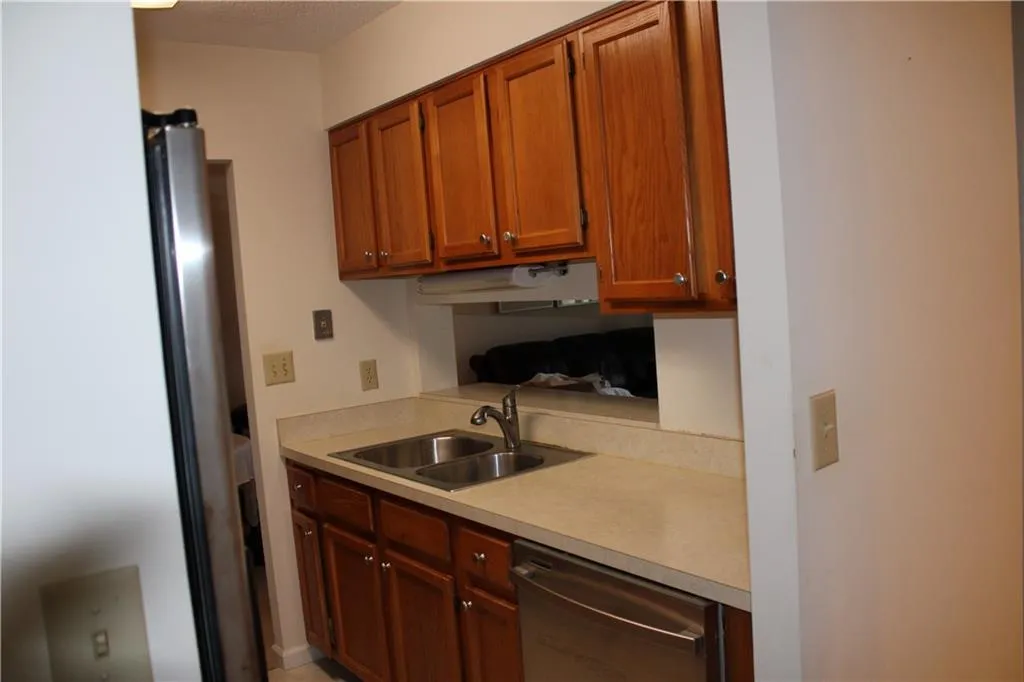 Kitchen featuring stainless steel dishwasher, sink, and view to Living Room.