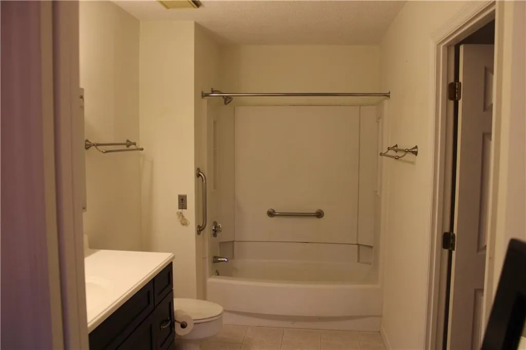 Full bathroom with vanity,  shower /  tub combination, tile floor. View from bedroom.