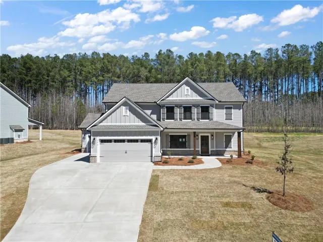 View of front of property featuring board and batten siding, covered porch, a shingled roof, a front yard, and concrete driveway