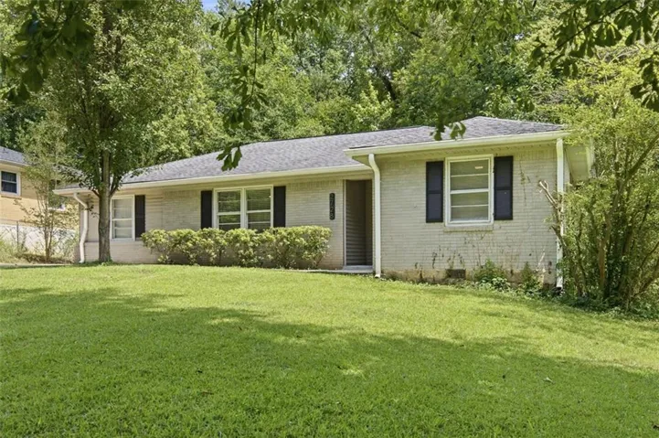 Single-story residence featuring light-colored brick siding, dark shutters, and a dark shingled roof