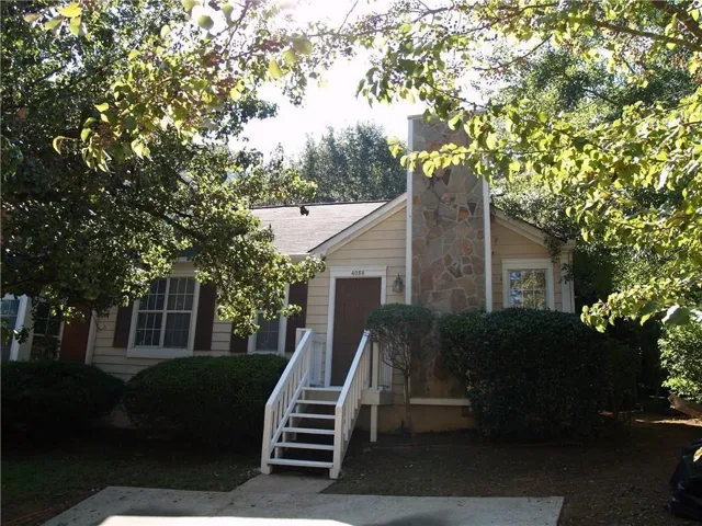 Siding exterior with a prominent stone-clad chimney and white-painted entry steps