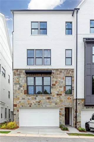 Contemporary townhouse exterior featuring a white painted brick upper facade and a natural stone lower facade