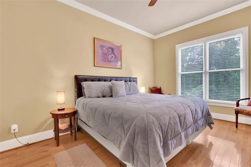 Main floor guest Bedroom featuring light wood-type flooring, ceiling fan, and crown molding