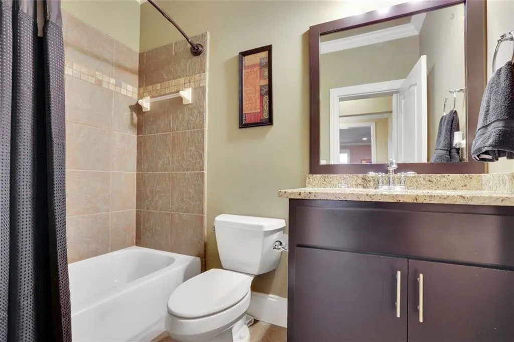 Full bathroom featuring shower / bath combo with shower curtain, ornamental molding, toilet, and vanity on basement level