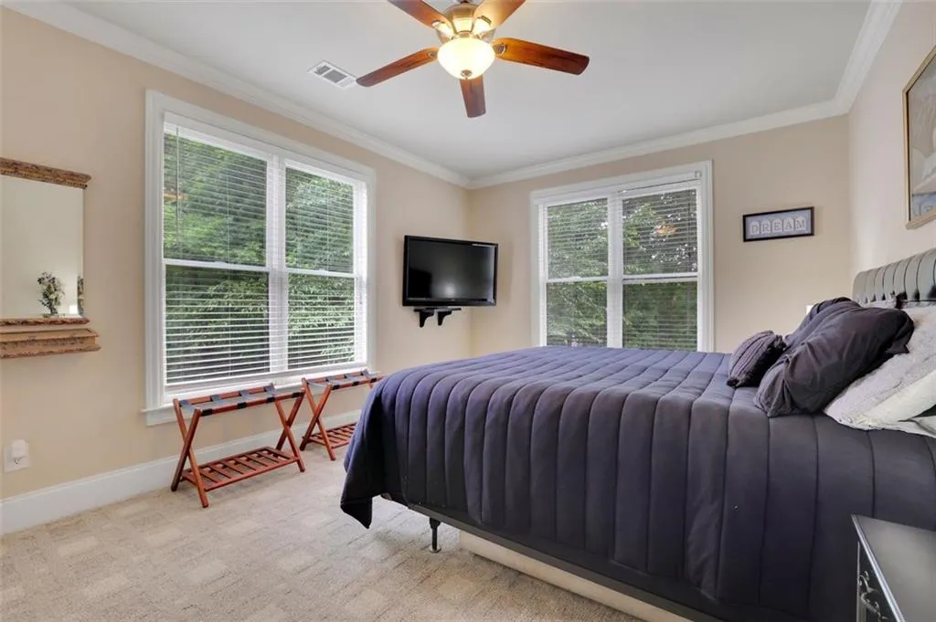 Carpeted basement bedroom featuring ceiling fan, ornamental molding, and multiple windows