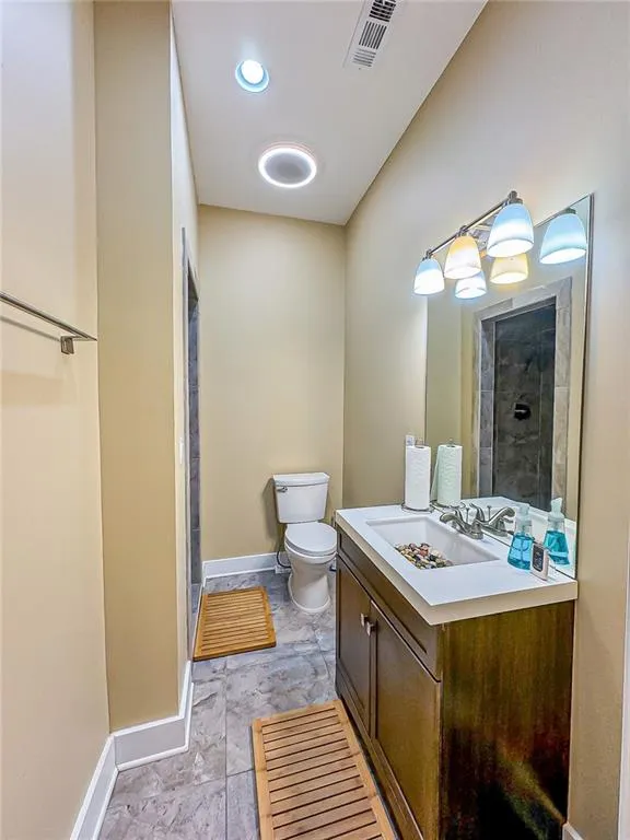 Bathroom (sub basement level) with shower, toilet, vanity and tile flooring